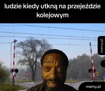 Mężczyzna na tle opuszczonych zapór na przejeździe kolejowym.