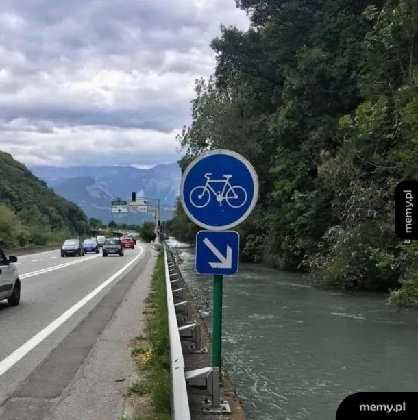 Znak droga dla rowerów nad rzeką obok ruchliwej autostrady z tabliczką wskazującą w dół do wody