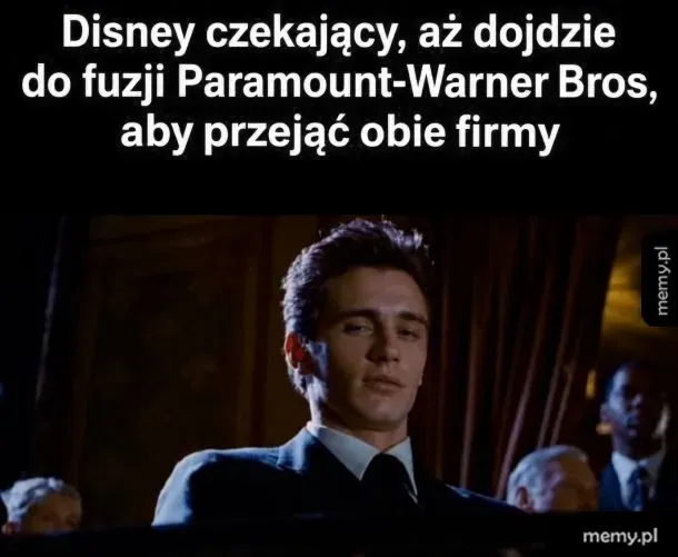 Mężczyzna w garniturze uśmiecha się chytrze w kinie