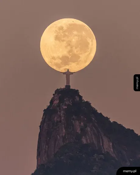 Pomnik Chrystusa Odkupiciela w Rio de Janeiro wydający się podtrzymywać wielki księżyc